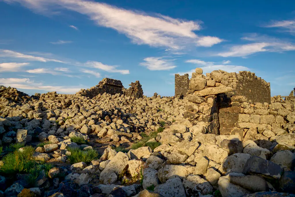 Tumbled basalt blocks and a standing building at Umm el-Jimal, Jordan