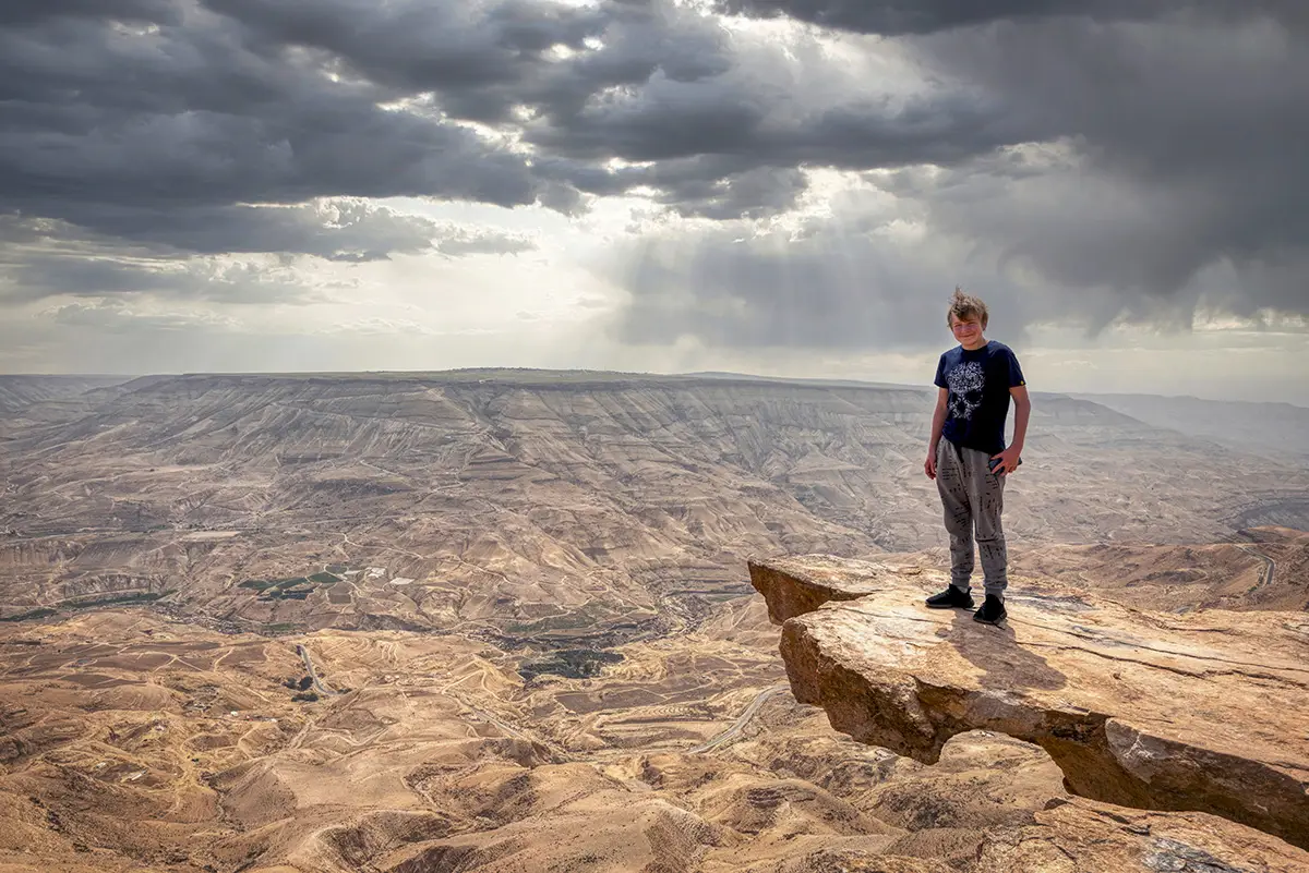 A visitor standing on a rock above the canyon of Wadi Mujib, Jordan